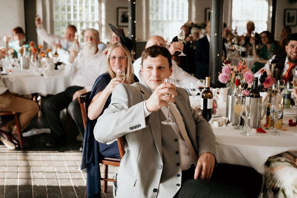 A wedding reception scene showing guests dancing and celebrating in an elegant indoor venue with white decor.