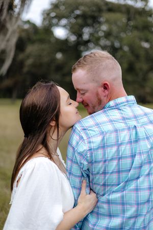 A romantic couple in a plaid shirt and white top share tender moments together in an outdoor setting.