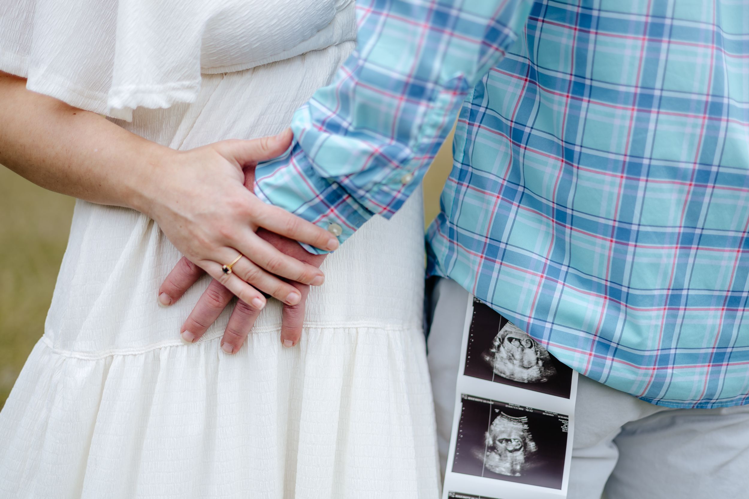 A couple holds hands while wearing coordinating blue plaid and white outfits during an outdoor photo session.