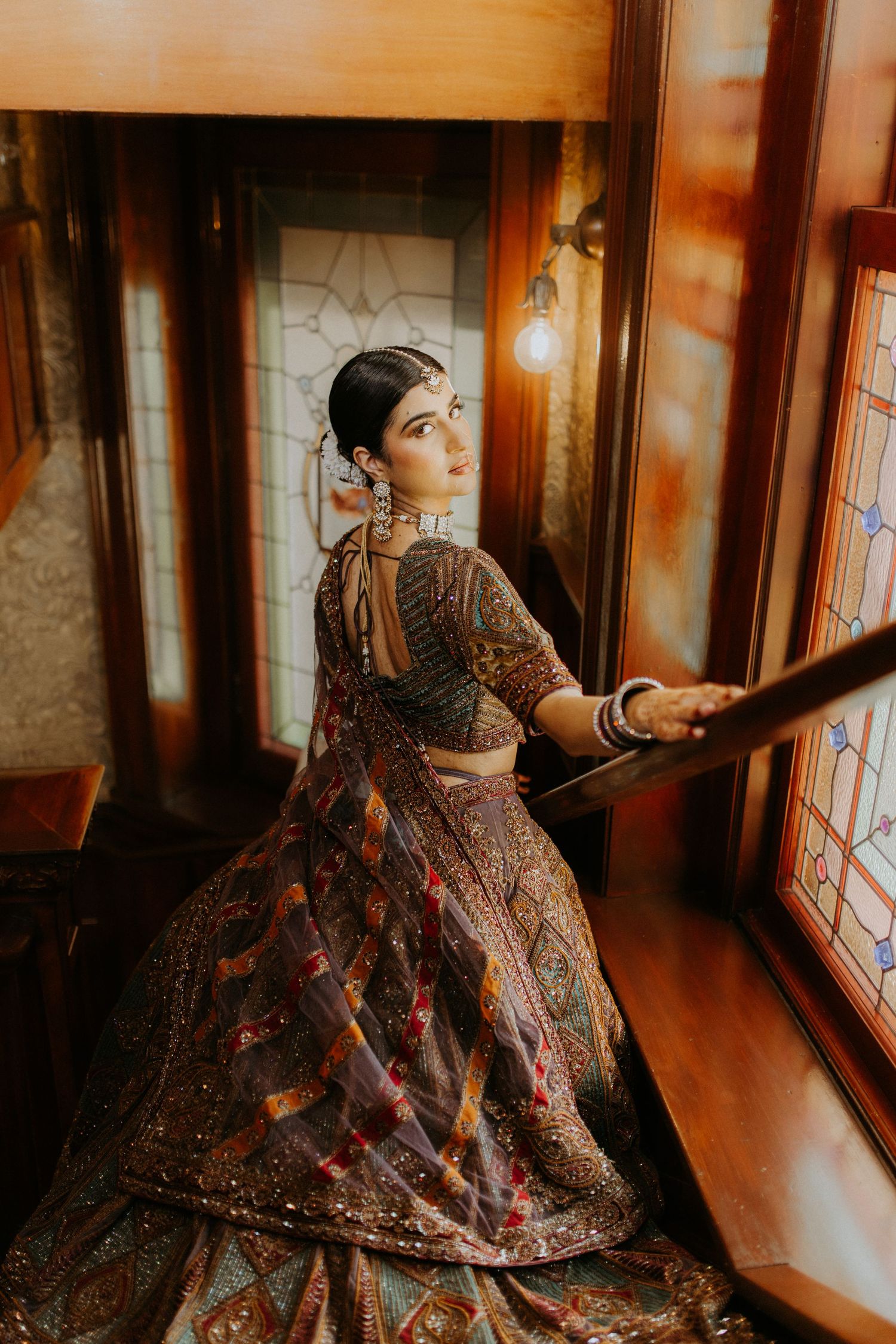 Traditional bridal attire showcased in warm lighting as figure poses gracefully by ornate window.