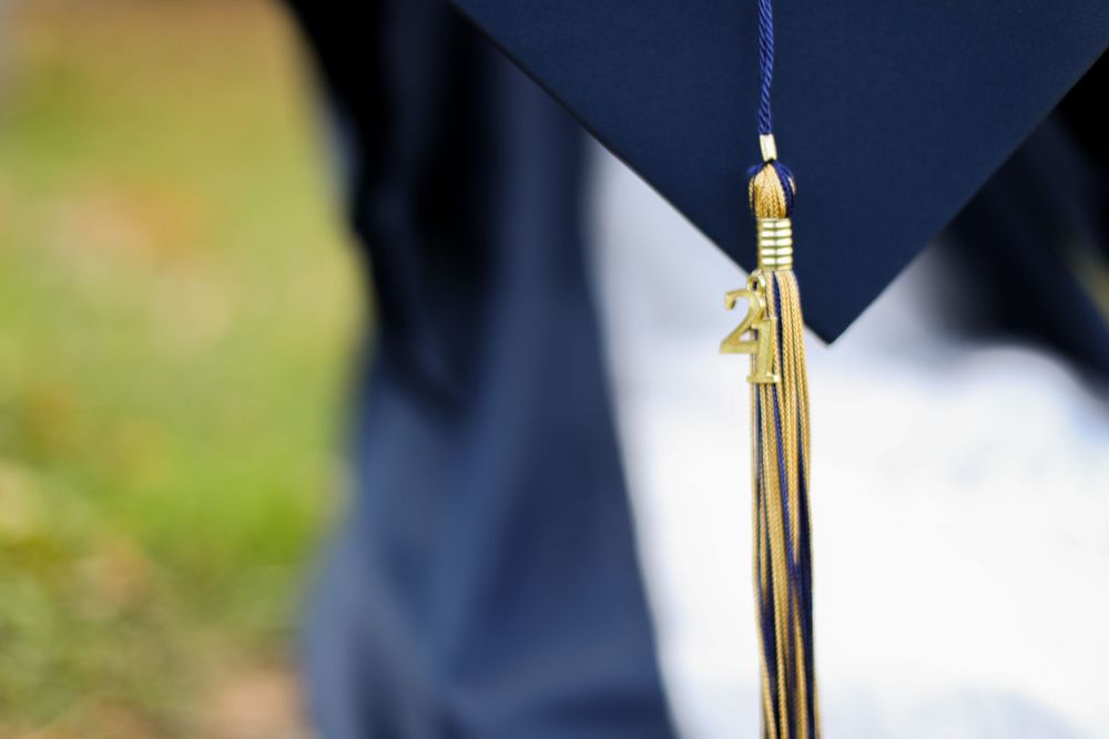 Close-up detail of graduation cap tassel against a navy blue gown.