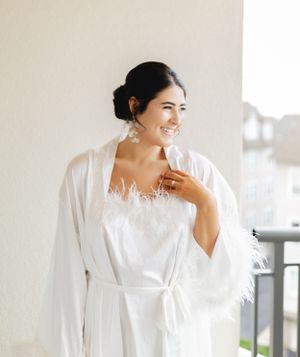 An excited gesture captured during wedding preparations in a white feathered robe.