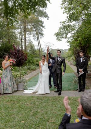 Wedding celebration in an outdoor garden setting with celebratory poses.