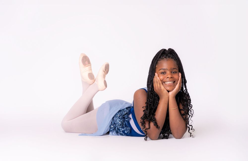 Studio portrait of someone laying on the floor in casual attire against white background.