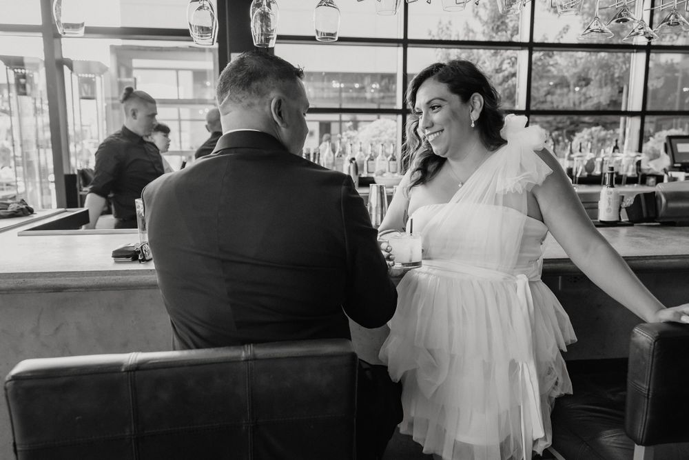 Romantic couple shares an intimate moment at a restaurant bar in elegant black and white photography.