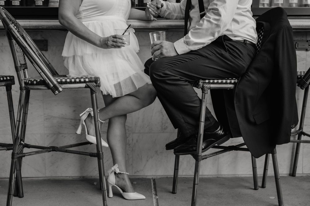 Closeup of elegantly dressed couple sitting at bar stools showing formal attire and heels.
