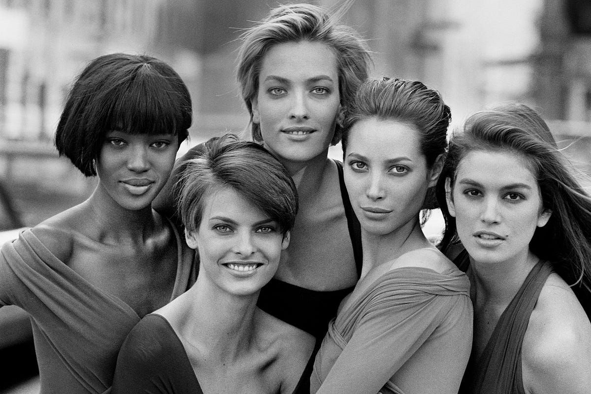 Black and white portrait of five fashion models posing together in a glamorous professional photo shoot.
