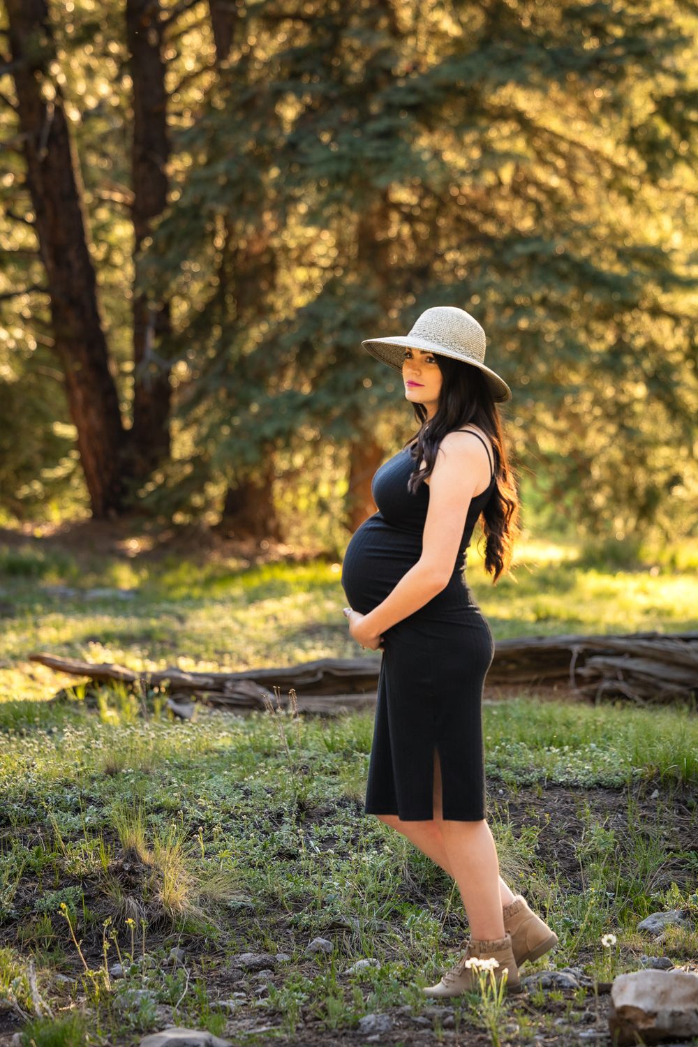 Mountain Maternity photograph with sunset, pine trees, and mom looking off into the distance, showcasing baby bump.