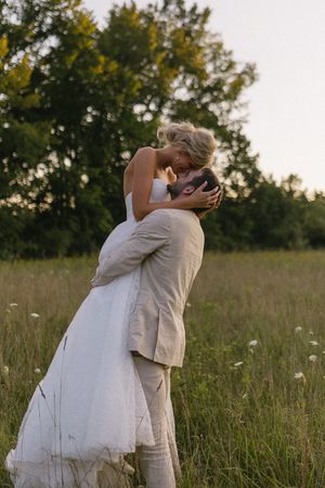 A romantic moment between newlyweds in a golden summer field.
