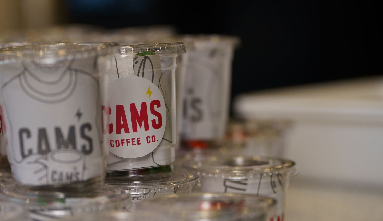 Glass jars with Cam's Coffee Co branding lined up on a counter.