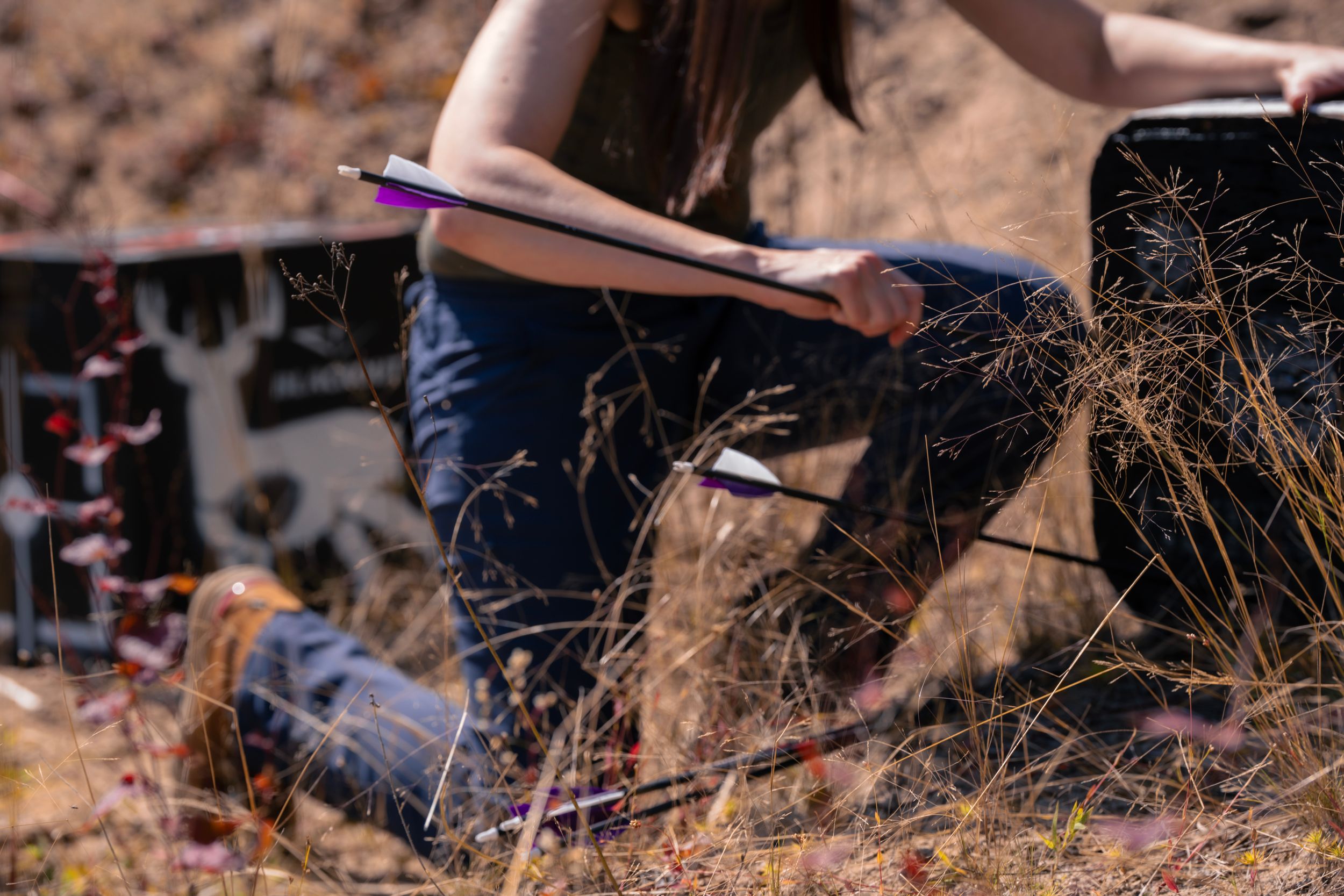 Writing or sketching materials laid out against dry grass and natural terrain.