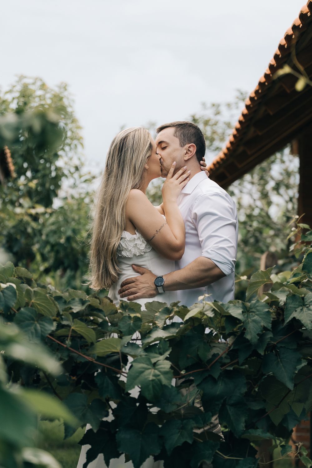 casal de noivos se beijando em ensaio pré wedding ao ar livre com natureza ao redor e luz natural