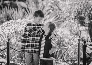 A couple in plaid shirts share a tender moment together on a wooden fence in a black and white photograph.