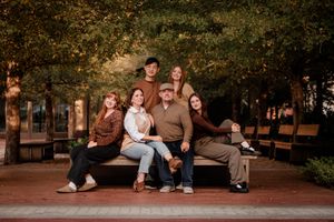 A group sits together on brick steps surrounded by autumn foliage in a park-like setting during a photo session.