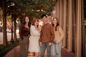 A group of friends walk together and laugh in a warmly lit outdoor hallway at sunset.