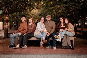 A group of people sitting together on brick steps during an outdoor photo session at dusk.