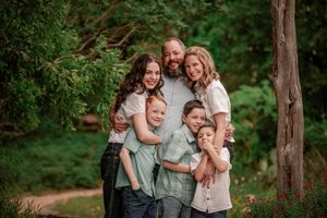 Family enjoying playful moments together in a wooded outdoor setting during a lifestyle photography session.