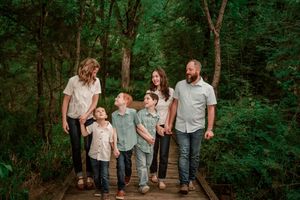 A group of people walk together through a lush green forest setting during a photo session.