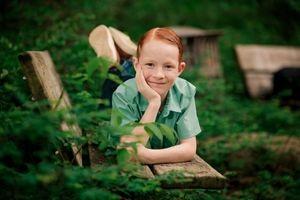 A child in a green shirt plays and explores outdoors in a lush garden setting.