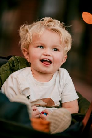 A series of candid shots showing a happy toddler with curly blonde hair wearing a white t-shirt and expressing joy.