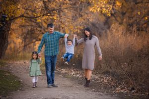 Family walking together on an autumn path surrounded by golden foliage during a fall photoshoot.