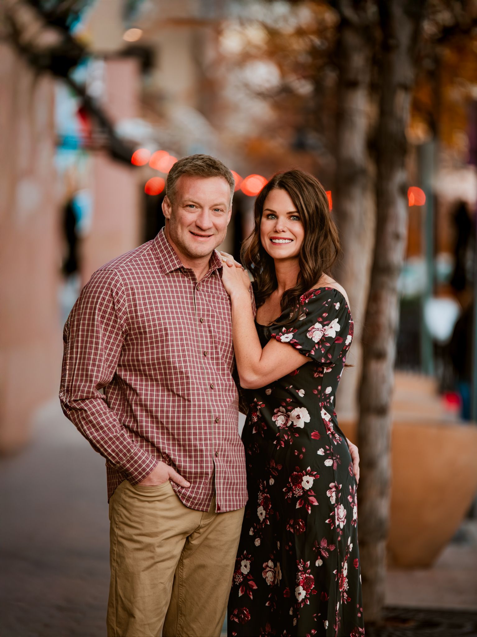 A couple shares a joyful moment together on a city street during a romantic evening photoshoot.