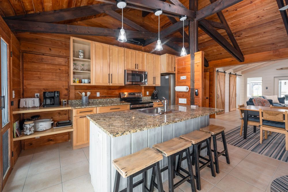 Modern industrial-style restaurant interior with wooden walls, exposed beams, and bar seating in a rustic setting.