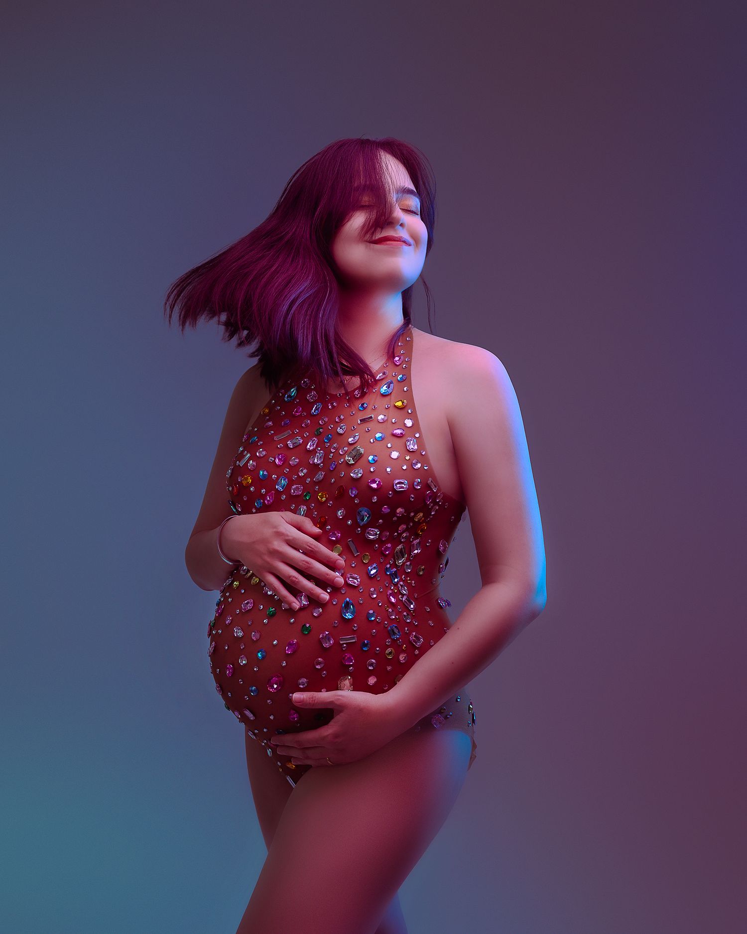 Woman in sparkling red dress posing dramatically in moody purple lighting.