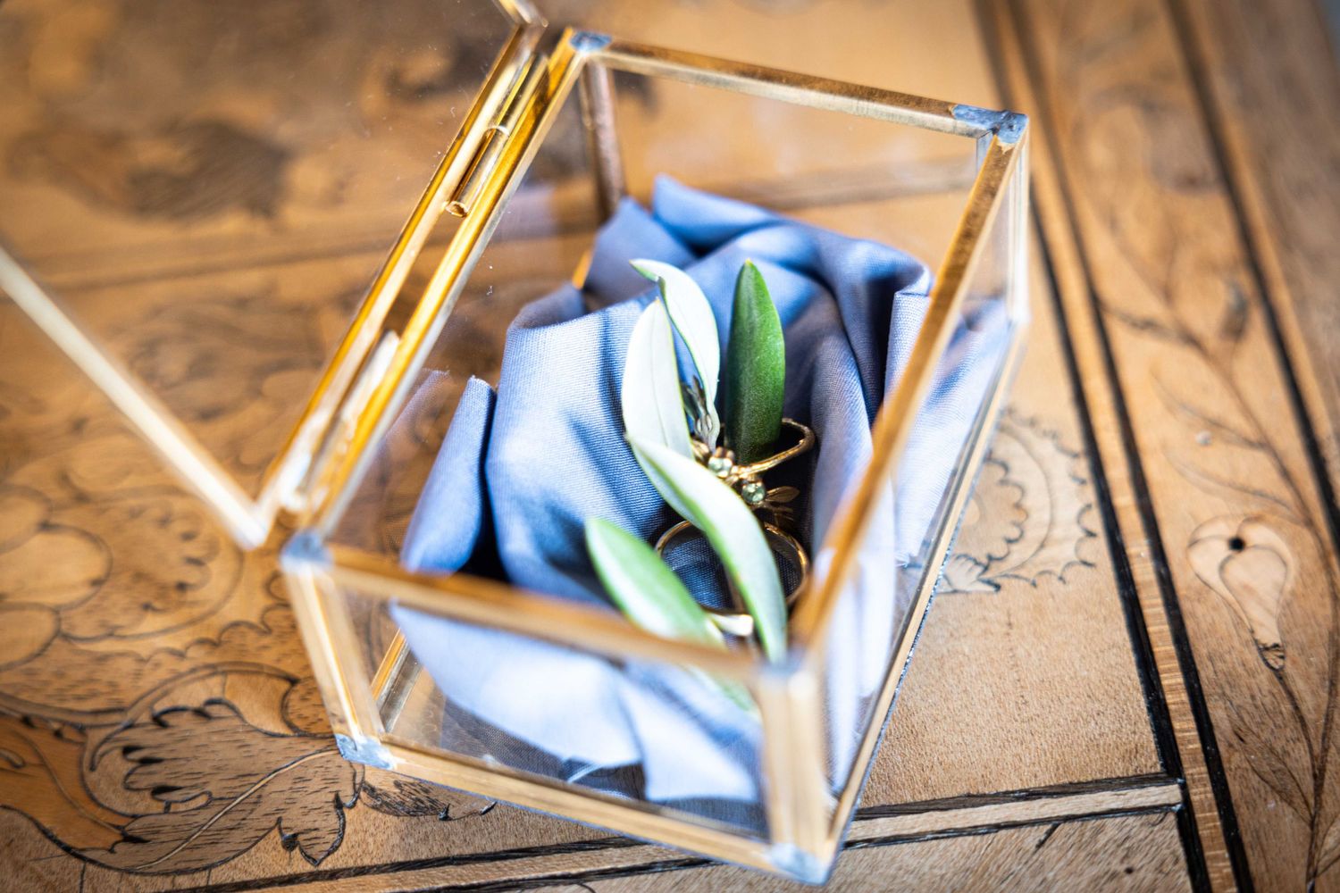 Wedding rings and delicate pink roses arranged on weathered wood with lace details.