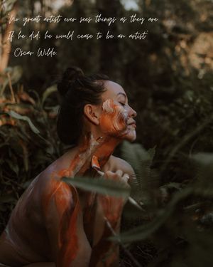 Artistic portrait of a person covered in orange paint looking up against a dark green foliage background with text overlay.