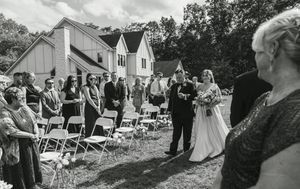 Wedding ceremony setup with white chairs on lawn and guests arriving.