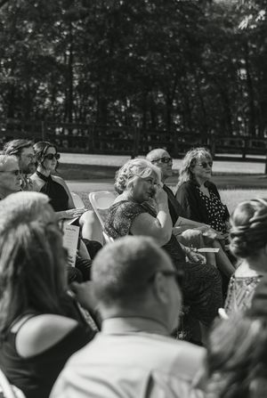 Black and white photo of wedding guests watching a ceremony outdoors.