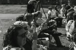 Black and white photo of wedding guests sitting outdoors on the grass.