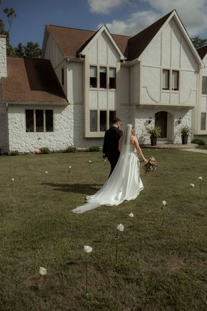 A sequence showing a bride walking across a church lawn with her dress trailing behind in the breeze.