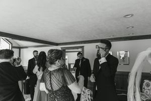 Vintage black and white photo of people socializing at an indoor wedding reception.