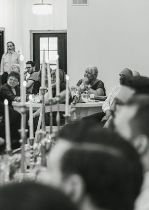 Black and white photo of wedding reception tables with guests and candlelight settings.