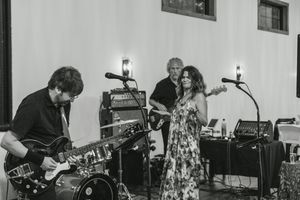 Band performing on stage with guitars and drums during a wedding reception.