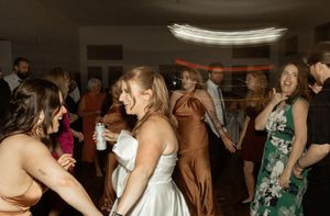Wedding reception party scene with guests dancing and celebrating in dimly lit venue.