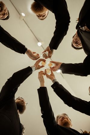 Business team raising champagne glasses in a celebratory toast from below view.