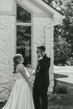 Black and white photos of a couple's first look moment outside a white stone church.