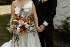Wedding party celebrates with rustic fall-themed floral bouquets featuring roses and dried elements in earth tones.