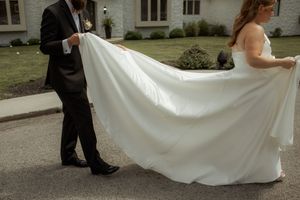 A series of photos showing the train and movement of a flowing white wedding dress against a stone building backdrop.