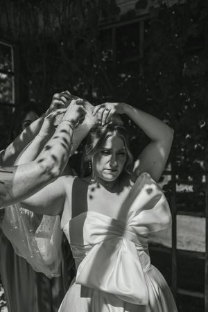 Black and white artistic photo of a woman in a white dress with dappled sunlight and shadows.
