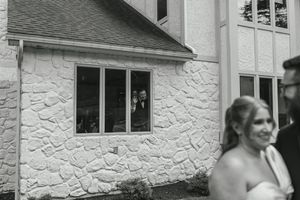 Black and white photo showing the exterior of a white stone building with wedding guests.