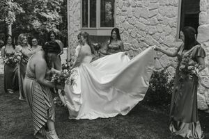 Multiple shots of a bride's dress being arranged on stone steps by wedding attendants.