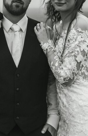 Close-up details of wedding attire showing a black suit and lace wedding dress.