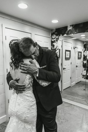 Black and white emotional wedding moment captured in venue hallway.