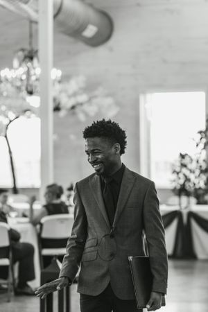 Wedding guest in grey suit smiles warmly during reception celebration.