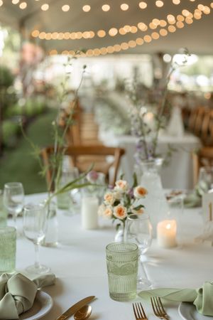Elegant wedding reception table setting with string lights, delicate floral centerpieces and mint green accents.
