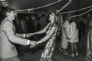 A couple dancing energetically in a vintage black and white photo at what appears to be a social gathering or party.